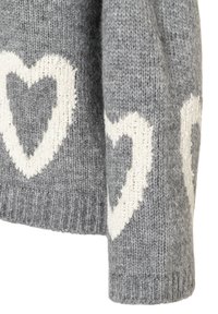 Grauer Wollpullover mit großen weißen Herzmustern. Die Textur ist gestrickt, mit einem gerippten Bund am unteren Ende für einen guten Sitz.