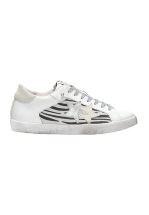 Sneaker bianca con accenti a forma di stella argentata, strisce zebrate nere sui lati, lacci grigi e una suola in gomma texturizzata.
