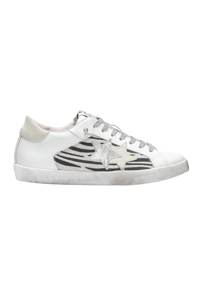 Sneaker bianca con accenti a forma di stella argentata, strisce zebrate nere sui lati, lacci grigi e una suola in gomma texturizzata.