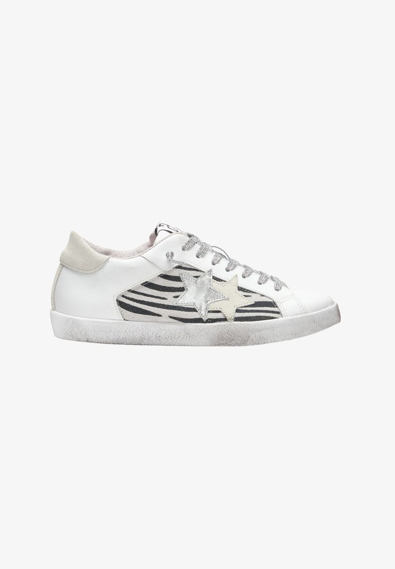 Sneaker bianca con accenti a forma di stella argentata, strisce zebrate nere sui lati, lacci grigi e una suola in gomma texturizzata.