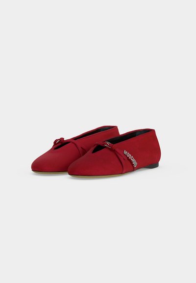 Paire de chaussures plates rouges à bouts pointus, avec une fine bride et un logo métallique "Moschino" sur le côté.