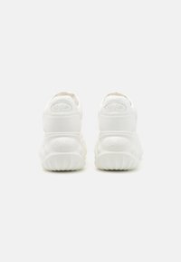 Zapatillas blancas con suelas de goma texturizada, diseño redondeado y logotipo en relieve en el talón. Material superior suave con una tira en la parte trasera para facilitar el calzado.