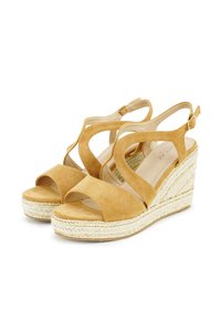 Suede wedge sandals in mustard yellow with open toes, crisscross strap design, and jute-wrapped wedge heel. Adjustable ankle strap detail.