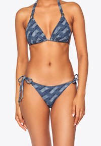 Costume da bagno a motivo denim, caratterizzato da un top triangolare con spalline a halter e fascia, e un bikini con slip laterali da annodare con un design intrecciato in diverse tonalità di blu.