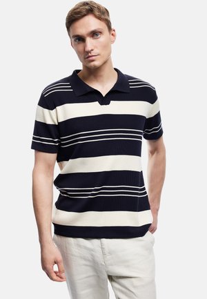 Marineblå og cremefarvet stribet polo T-shirt med kort krave, struktureret strikstof og åben placket. Stylet med lyse bukser.