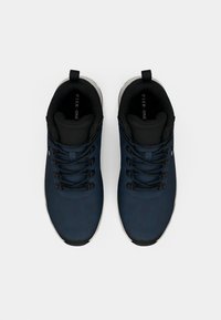Navy blue ankle shoes with a smooth fabric upper, black laces, and a white sole. Features a padded collar and interior for comfort.