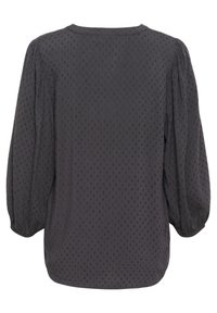 Zwarte blouse met driekwart pofmouwen, textuurstof met kleine verhoogde stippen en een ronde halslijn. Geen zichtbare sluitingen.