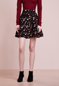 Mustat kukkakuvioiset hameet, joissa on levenevä muotoilu, pienillä vaaleanpunaisilla ja kermakukilla. Yhdistetty mustiin nilkkasaappaisiin ja marooniin pitkähiharaiseen paitaan.