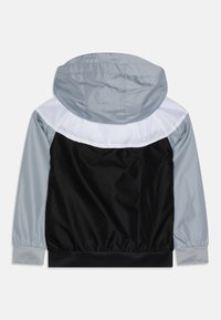 Mikina s kapucí s barevným blokem v šedé, bílé a černé barvě. Vyrobena z lehkého, hladkého materiálu s elastickými manžetami.