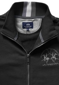 Zwarte zip-up jack met grijze accenten, fleece textuur, geborduurd polo-ontwerp en een grijze binnenkraag met strepen op de hals.