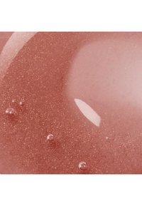 Gros plan sur un gel brillant de couleur rose avec de fines particules pailletées dorées et de petites bulles d'air à l'intérieur.