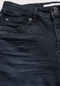 Jeans de mezclilla oscura con una textura suave, que presentan un bolsillo frontal, detalles de botones plateados y un diseño ligeramente desgastado.