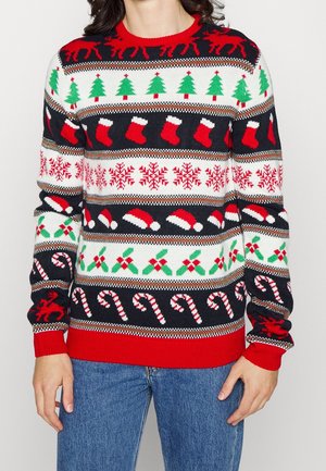 Person trägt einen Weihnachts-Pullover mit Mustern aus roten Rentieren, grünen Tannenbäumen, roten Strümpfen, Schneeflocken, Weihnachtsmannmützen, Stechpalmen und Zuckerstangen.