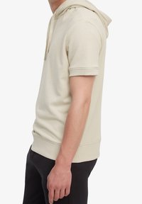 Felpa con cappuccio a maniche corte in cotone beige chiaro con polsini e orlo a costine. Presenta un logo leggero sul petto. Vestibilità casual.