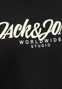 Fekete, pamutból készült póló, amelyen nagy, fehér írásos felirat található: "Jack & Jones", és kisebb szöveg: "WORLDWIDE STUDIO". Simaszerkezet.