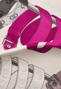 To mønstrede bælter vist på en hvid baggrund. Det ene er livligt pink med en sølvspænde, det andet er grå med et logomønster.
