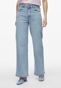 Jeans anchos de denim azul claro con cintura alta, bolsillos frontales y detalles de costura sutiles. Textura suave y ajuste clásico.