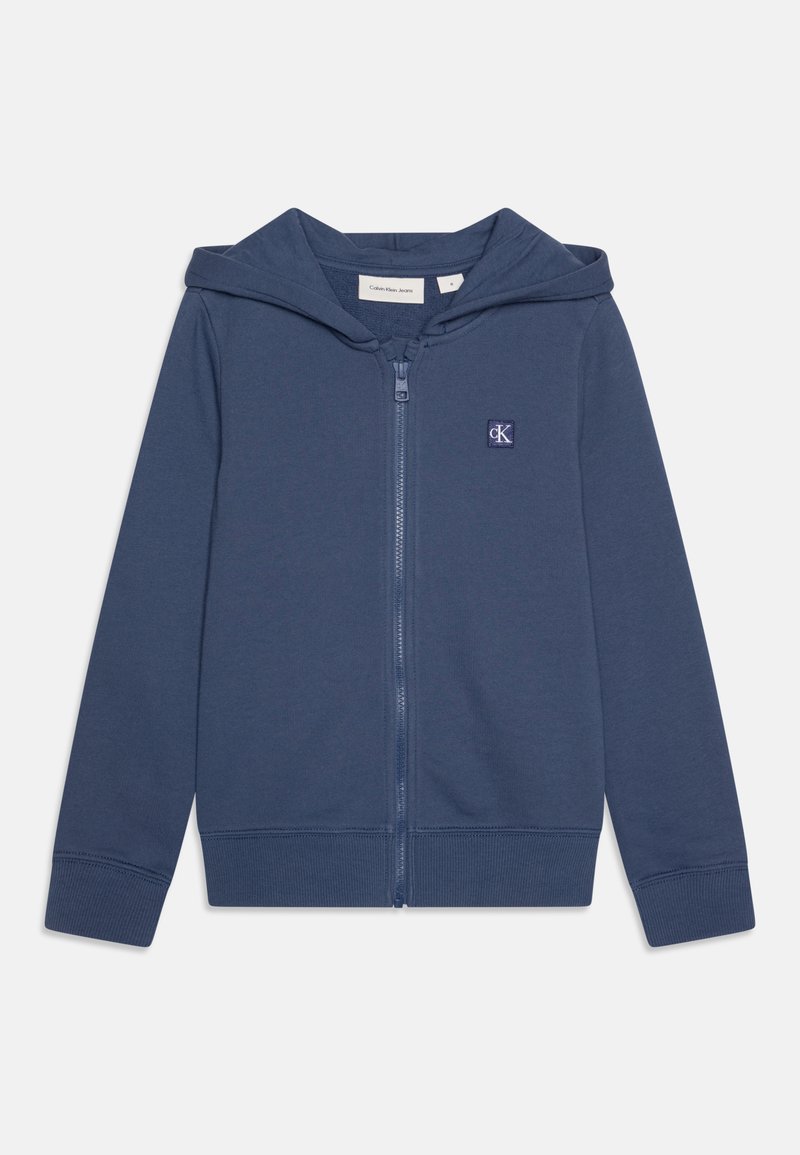 Marinblå zip-up hoodie med fodrad huva, framfickor, ribbade mudd och nederdel, samt en liten CK-logotyp på vänster bröst. Tillverkad av mjukt tyg.