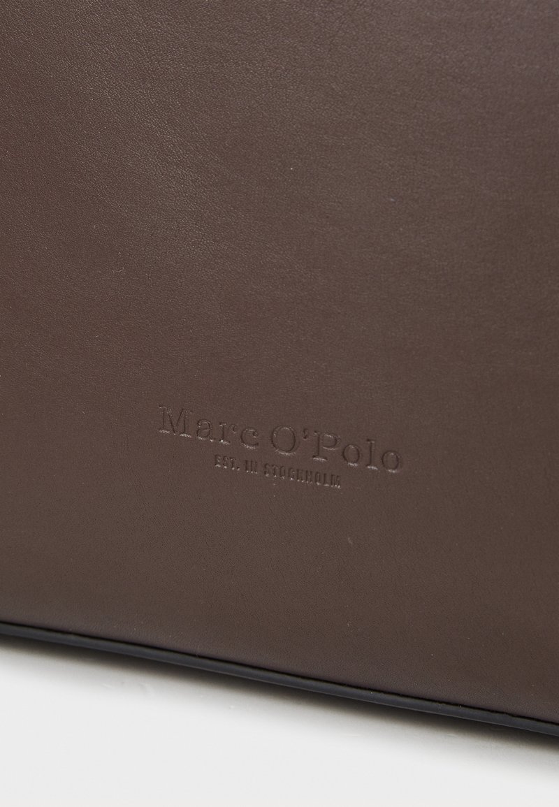 Braune Lederhandtasche mit geprägt "Marc O'Polo"-Logo, glatte Textur, rechteckige Form und subtile Strukturdetails.