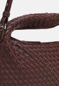 Sac à main en cuir tressé de couleur bordeaux foncé avec une surface texturée, doté d'une poignée robuste et d'accents subtils de couture rouge.