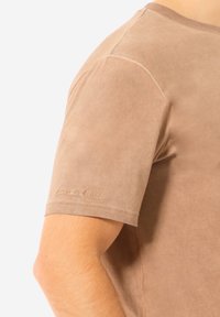 Kurzarm-T-Shirt in hellbraunem Wildleder-Finish, mit dezentem gesticktem Logo auf dem linken Ärmel. Glatte Textur mit taillierter Form.