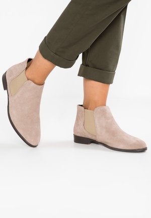 Taupe Wildleder-Ankle Boots mit elastischen Seitenpaneelen, niedrigem Absatz und abgerundeter Zehe. Merkmale sind eine glatte Textur und ein minimalistisches Design.