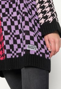 Strickpullover mit Schachbrettmuster in Schwarz, Lila und Pink, mit einem schwarzen gerippten Saum und einem angenähten "RAGGED"-Etikett.