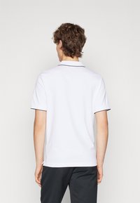 Polo bianco a maniche corte con colletto, caratterizzato da bordi neri lungo il colletto e le maniche. Tessuto morbido con un taglio classico.