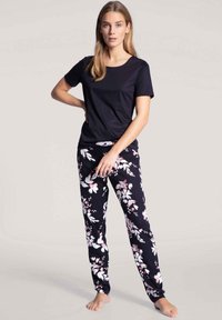 Black crew-neck t-shirt paired with black floral pajama pants featuring pink and white flower patterns. Soft fabric, relaxed fit.