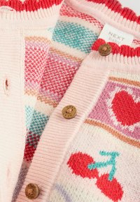 Strickjacke für Babys in Pastellrosa mit mehrfarbigen Mustern, darunter Kirschen und Herzen, mit Holzknöpfen und geripptem Kragen.