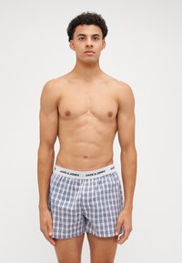 Blauw-witte geblokte boxershorts met een elastische tailleband, voorzien van het logo "JACK & JONES". De stof lijkt licht en ademend te zijn.