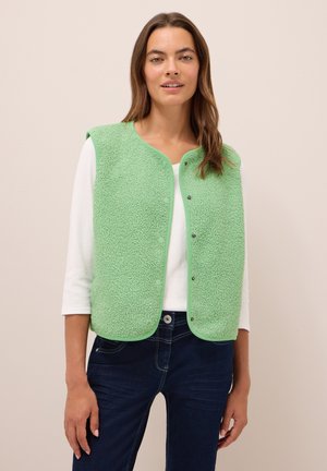 Groene fleece vest met een gestructureerd oppervlak, ronde halslijn en drukknoopsluiting. Draag over een wit, langemouwen shirt, in combinatie met donkere jeans.