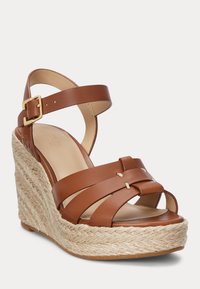 Sandalo con zeppa in pelle marrone, con fasce incrociate, dotato di una suola in juta simile a quella degli espadrillas e un'elegante fibbia dorata sulla cinghia alla caviglia.