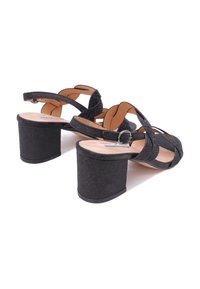 Sandali neri con plateau, dotati di cinturini testurizzati, fibbia circolare e tacco grosso. Il materiale sembra morbido con una leggera lucentezza.