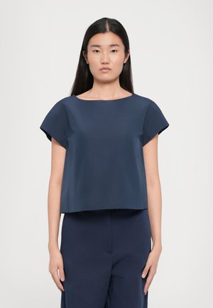 Top corto blu navy a maniche corte con scollatura rotonda ampia e una texture liscia e setosa. Taglio a silhouette squadrata.