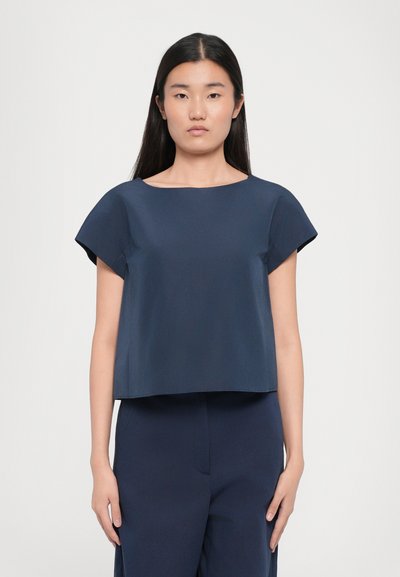 Ναυτικό μπλε, κοντομάνικο crop top με φαρδύ, στρογγυλό λαιμό και λεία, απλή υφή. Κομμένο σε κουτί σιλουέτα.