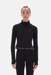 Juodas sportinis švarkas su aukštu apykakle, visiškai užtraukiamas, ir raštuotais rankogaliais. Yra prekės ženklo elastinis juosmuo. Pagamintas iš lygios, tamprios medžiagos.