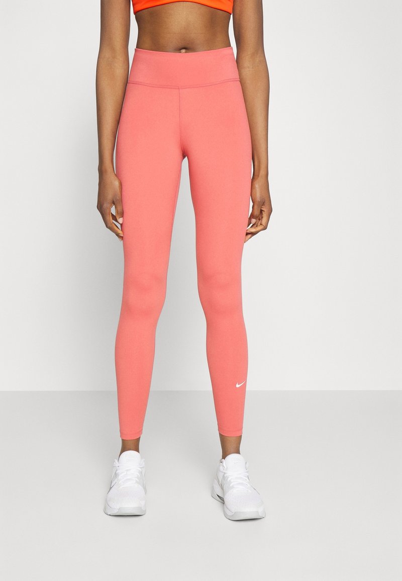 Růžové sportovní legíny vyrobené z elastického materiálu, s vysokým pasem a decentním bílým logem Nike na levém kotníku.