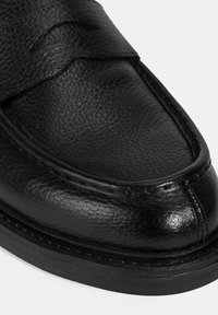 Zwarte lederen schoen met een glad, textuur oppervlak, gestikte details en een ronde neus. Bevat een contrasterende rubberen zool voor grip.