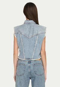 Gilet in denim con orlo sfilacciato, colore azzurro chiaro e design delle spalle strutturato. Presenta dettagli delle cuciture centrali e laterali.