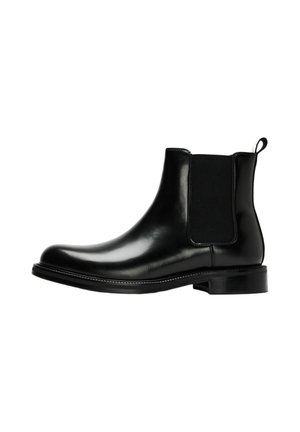 Bottine Chelsea en cuir noir à la cheville avec panneau latéral élastique, languette au talon, et petit talon empilé sur fond blanc.