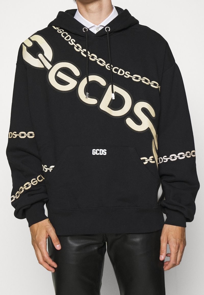 Felpa con cappuccio nera caratterizzata da un audace logo "GCDS" beige e un motivo a catena. Realizzata in tessuto morbido con tasca frontale e cappuccio con cordini.