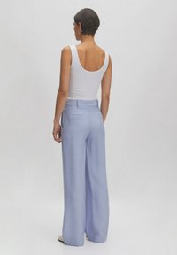 Lichtblauwe brede broek met een gestructureerde stof en twee achterzakken, gecombineerd met een getailleerd wit tanktop.