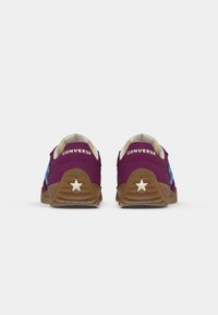 Converse sneakers in purple and blue suede with brown rubber soles, featuring star accents on the heel and a padded collar.