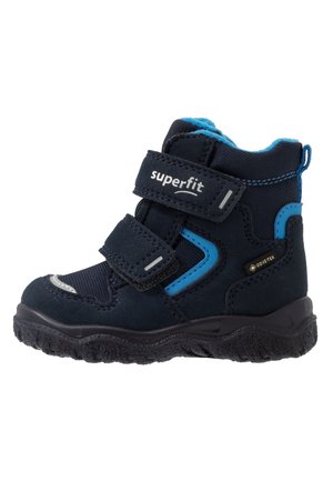 Botte d’hiver bleu marine pour enfant avec accents bleus, deux sangles Velcro, semelle noire robuste et étiquette imperméable Gore-Tex.