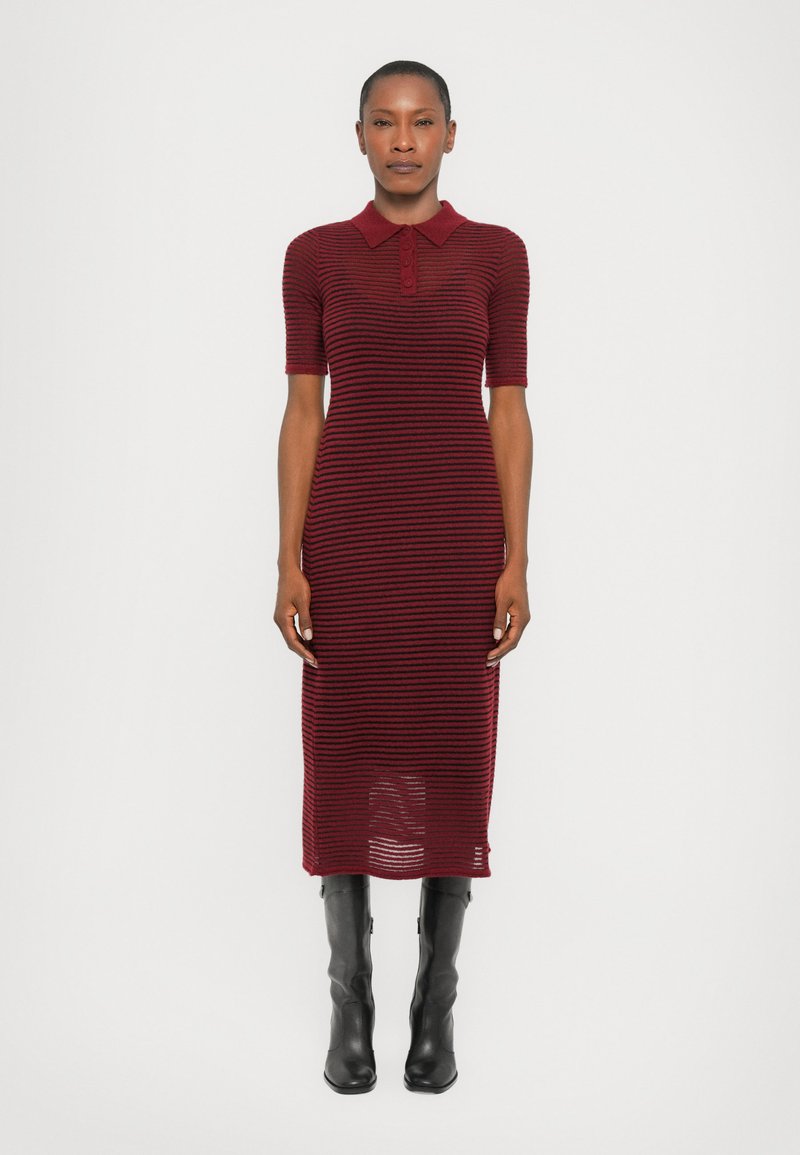 Knit dress with a polo collar, featuring red and burgundy horizontal stripes. Mid-length, short sleeves, textured fabric, paired with black knee-high boots.