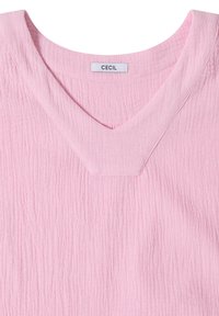Haut en tissu texturé rose clair avec large encolure en V et étiquette de marque visible « CECIL » au col.
