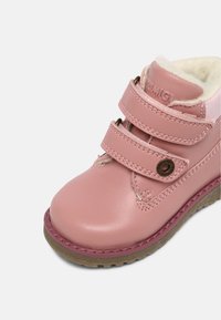 Bottine rose pour enfants avec double scratch, semelle en caoutchouc marron et doublure douce de couleur crème à l'intérieur.