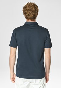 Polo shirt blu navy a maniche corte con colletto, texture liscia e orlo dritto, mostrato da dietro, su uno sfondo semplice.