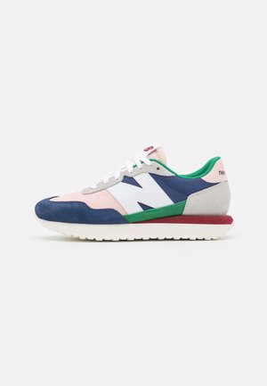 Low-profile sneaker med ruskindsoverlays i navy, pink og grå, grøn stofforing, hvide snørebånd og et hvidt "N" logo på siden.